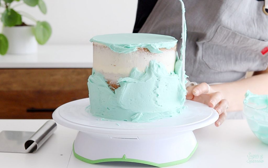 adding buttercream frosting to cake