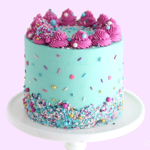 A colorful turquoise cake with magenta swirls on top