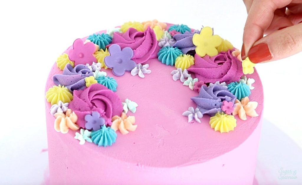 adding fondant flowers to cake