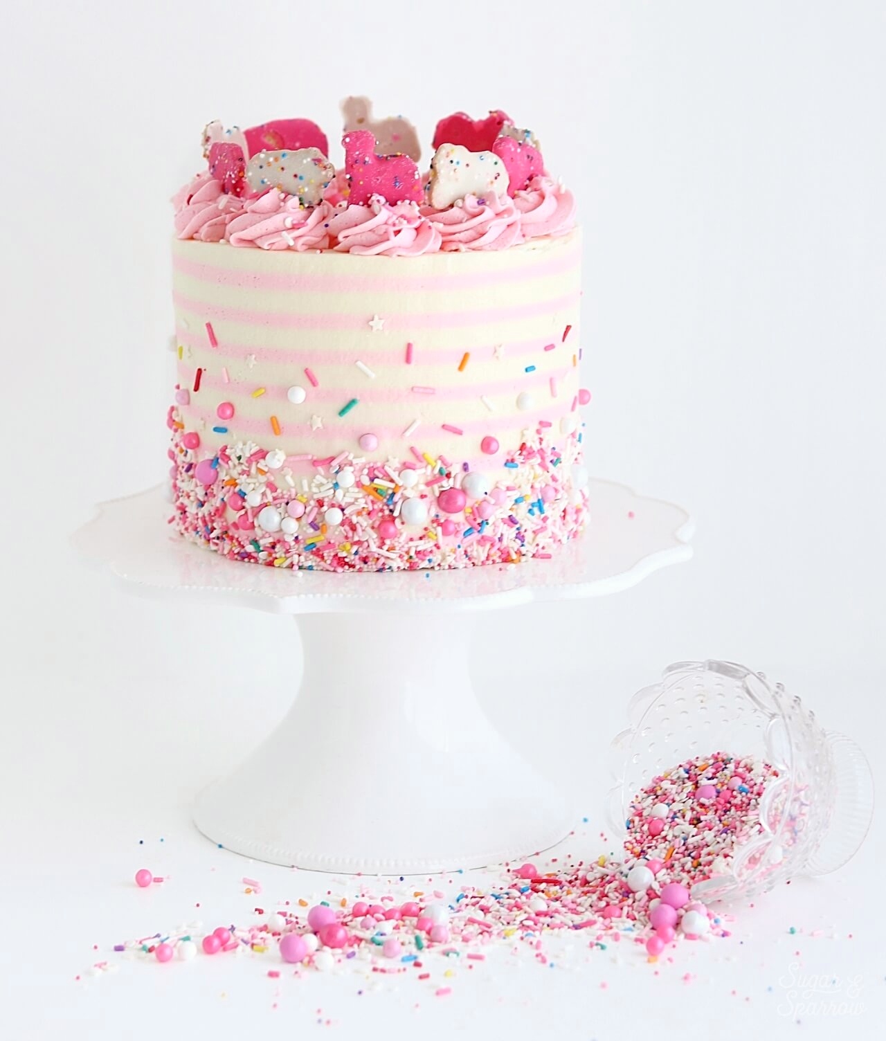 pink and white striped cake with sprinkles