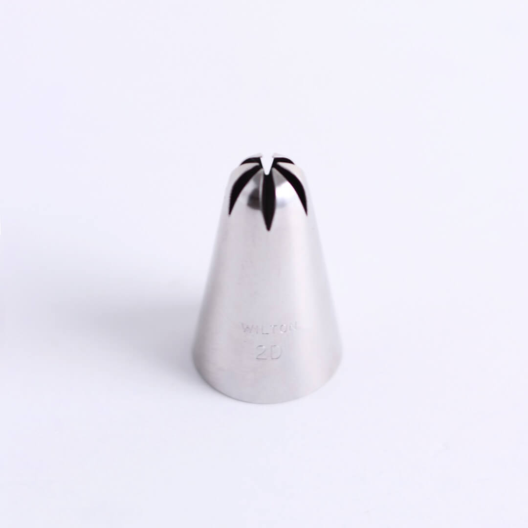 A metal icing tip (Wilton tip 2D) sits on a white background.