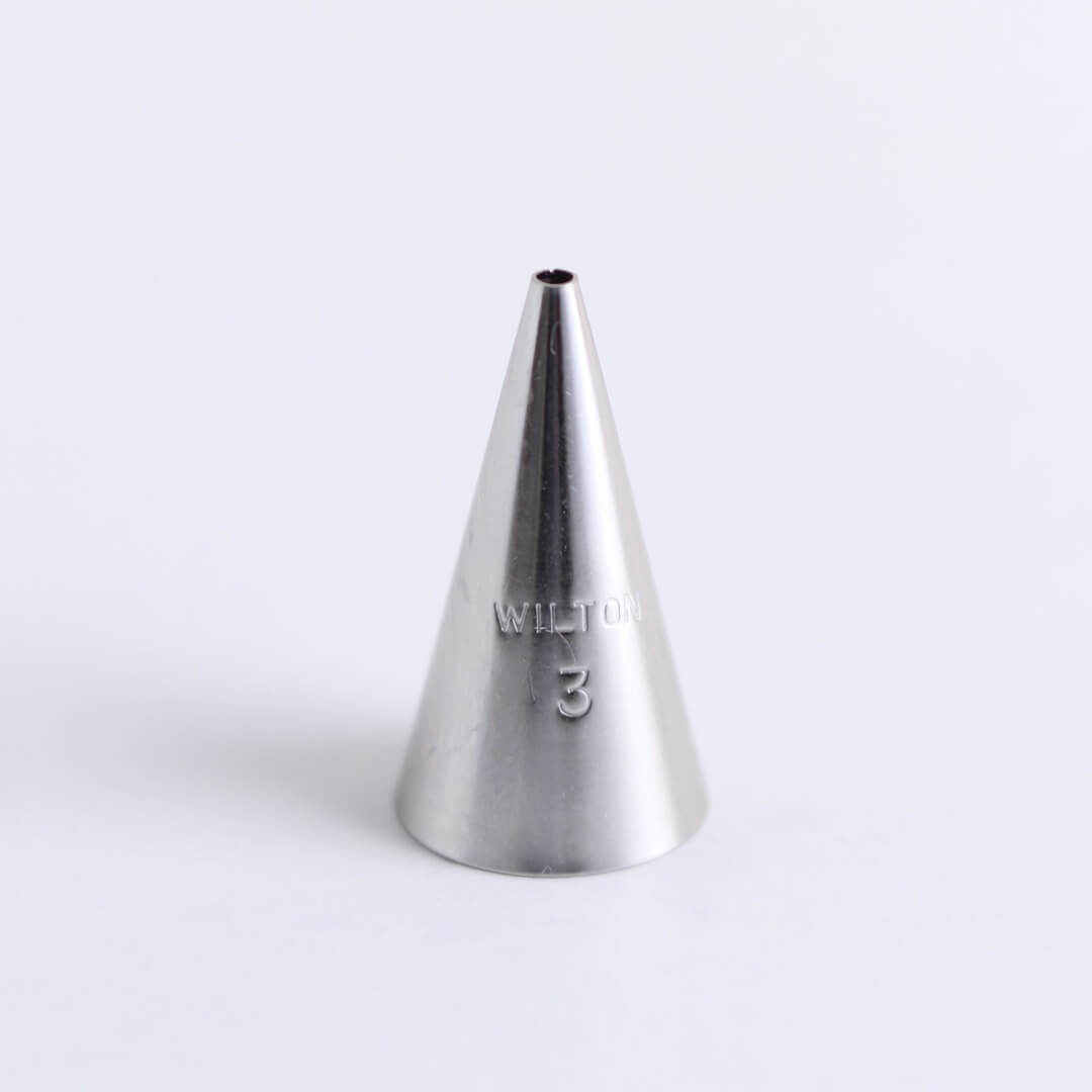 A metal Wilton icing tip (number 3) sits on a white background.